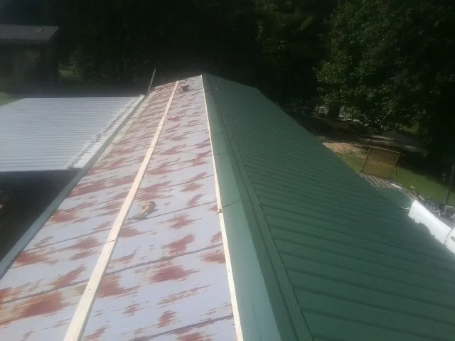 Old rusted panels beside newly installed green metal roofing — Wind Damage Roof Repair by Roofing Brothers in Caldwell